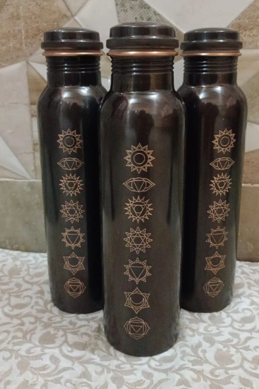 Three black water bottles with gold designs on a tiled floor.